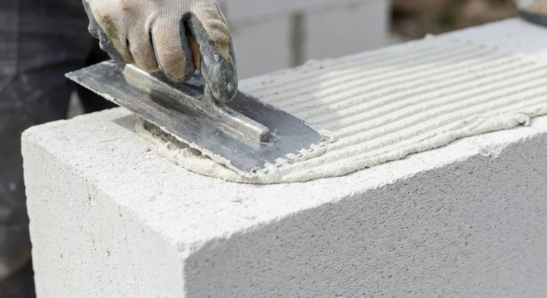 Application de la colle spéciale sur un bloc de béton cellulaire pour une cloison de 10 cm.