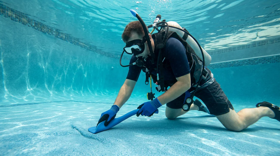 Technicien réparant une bosse sous le liner de piscine